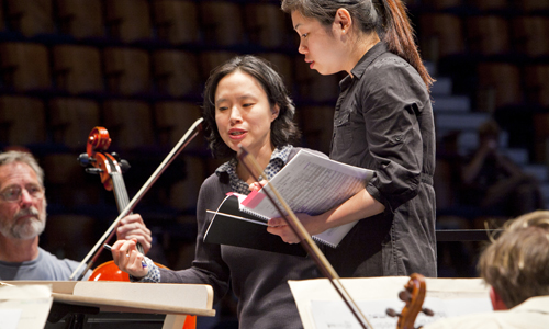 Guest conductor Carolyn Kuan instructs workshop participant Elim Chan. Photo by rr jones.